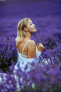 一位中年妇女坐在薰衣草田里享受香薰。