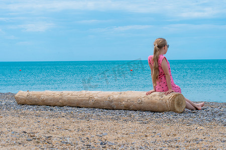 隐居摄影照片_日志女孩美丽的夏日海滩贝加尔湖徒步奥尔洪自然，青少年游客度假的概念天空旅行，隐居蓝色。