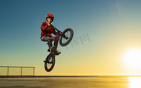 一名青少年 BMX 赛车手在滑板公园的泵道上表演特技。