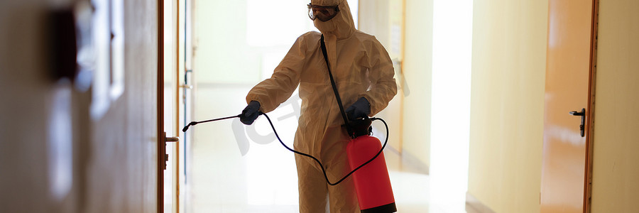 身穿防护服的病毒学家对公共和隔离区域的表面进行消毒