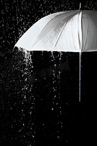 黑色背景雨滴下的白色雨伞
