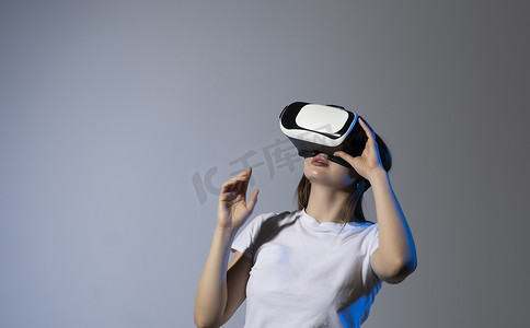 戴 VR 耳机的女性用手指触摸 VR 设备上的虚拟面板观看。 