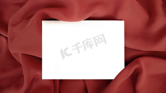 邀请函模板摄影照片_红色织物上的空空白明信片模板。
