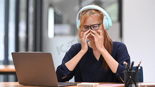 疲惫的亚洲女上班族在长时间使用笔记本电脑后出现视力模糊症状，感到眼睛疲劳紧张问题