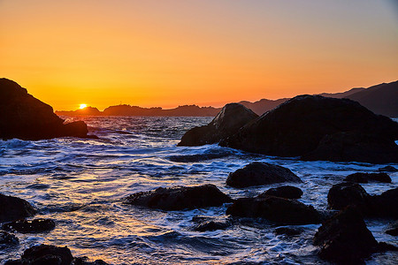 在被海浪和岩石覆盖的海滩上的日落黄金时刻
