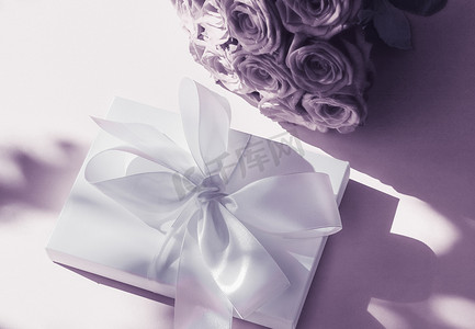 豪华假日丝绸礼盒和紫色背景玫瑰花束、浪漫惊喜和鲜花作为生日或情人节礼物
