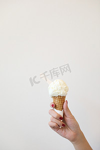 拿着冰淇淋摄影照片_女人的手拿着冰淇淋特写