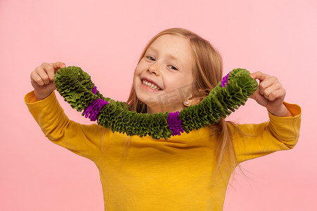 快乐孩子的肖像，脖子上戴着绿色花环，对着镜头微笑，玩得很开心