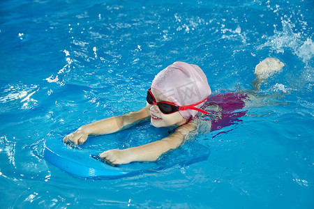 小女孩在带台球板的室内游泳池里学习游泳