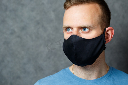 戴着黑色防护医疗面具抵御病毒的年轻男子。