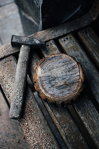 一把旧的老式锤子和一条长凳上放着锯末的圆松木条。