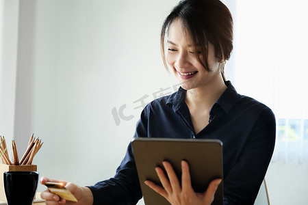 在线支付、年轻女性手持平板电脑和信用卡进行在线购物。