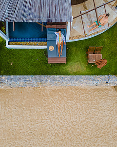 豪华别墅中的情侣在小型泳池中享受，俯瞰海洋和海滩
