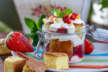 巧克力海绵蛋糕、生奶油或乳清干酪和新鲜草莓放在玻璃碗中的分层甜点。