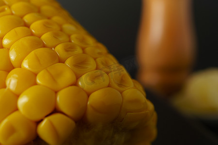 玉米穗的宏观特写，背景中有一个失焦的胡椒罐