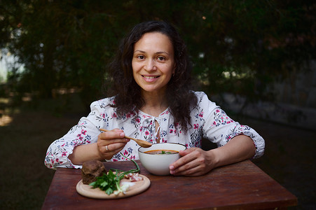 民间菜摄影照片_美丽的多民族妇女吃美味的自制新鲜烹制的乌克兰国菜 — 红甜菜根汤 — 罗宋汤