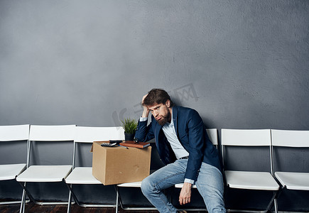 求职的男人摄影照片_一个穿西装的男人坐在椅子上，带着盒子求职抑郁症