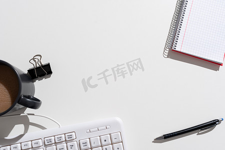 重要信息摄影照片_重要信息在桌子上呈现，周围有笔、笔记本、回形针、咖啡和键盘。