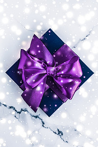 冬季节日礼盒，配有紫色丝绸蝴蝶结、大理石背景上的雪花，作为豪华美容品牌的圣诞和新年礼物，平铺设计
