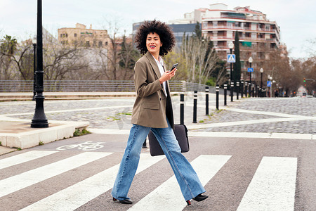 使用智能手机在人行横道上行走的女人