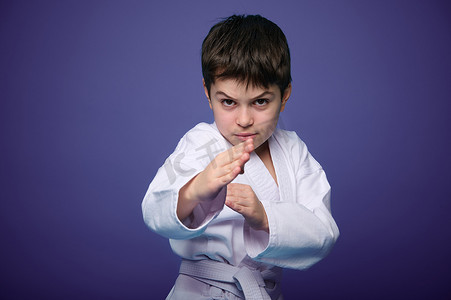 自信坚强的孩子，合气道战士在紫色背景下练习武术技能，并带有广告复制空间。