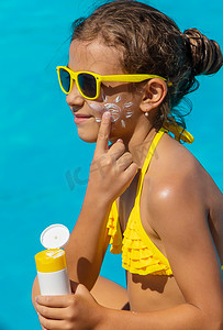 药健康摄影照片_孩子脸上泳池附近的防晒霜。