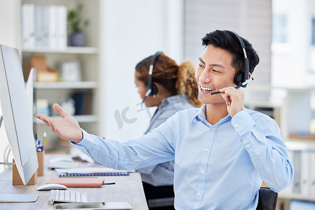 快乐、自信、乐于助人的呼叫中心代理在办公室的电脑上工作时用耳机交谈。