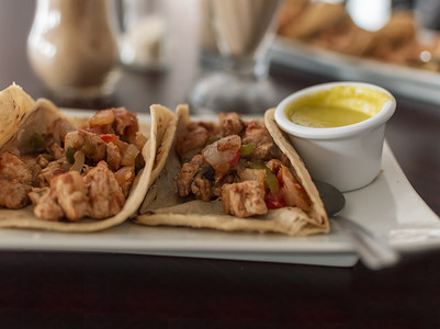 墨西哥餐厅摄影照片_墨西哥鸡肉炸玉米饼的特写，鸡肉炸玉米饼和莎莎酱放在桌子上，炸玉米饼放在桌子上