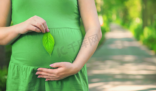 公园里的一名孕妇拿着一片绿叶。