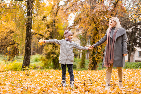 感恩节二摄影照片_母亲和女儿在秋天的黄色公园。