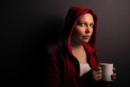 黑暗房间摄影照片_美丽的红戴头巾的女人喝咖啡