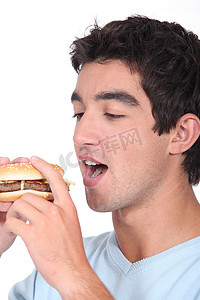 男孩吃汉堡摄影照片_吃汉堡的男孩