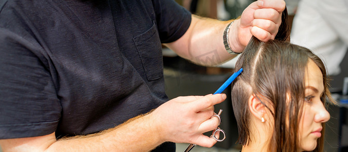 线条分割摄影照片_美发师将女性头发分成几部分，用梳子在美发沙龙特写中用手握住头发。