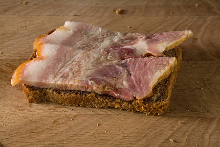 黑面包和咸猪油三明治，木板上有肉条