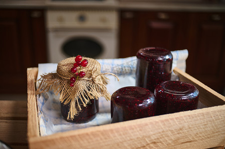 罐子里的浆果果酱倒置在板条箱上，果冻瓶装饰华丽，盖子上有粗麻布和红醋栗浆果