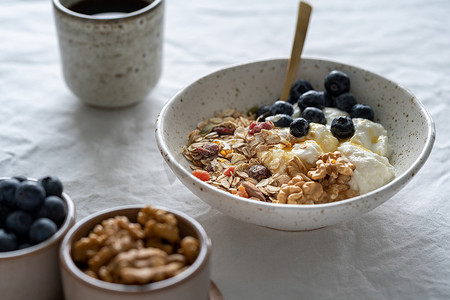 白桌背景碗中的健康生活方式早餐，包括麦片麦片和酸奶