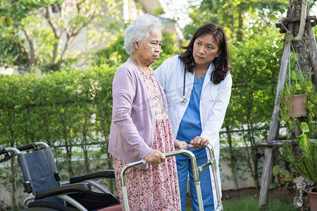 帮助和照顾亚洲老年或老年老妇妇女在快乐的新鲜假期在公园散步时使用健康状况良好的助行器。