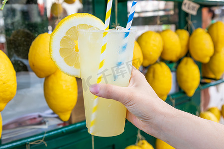 夏季柠檬果汁摄影照片_夏季白种人手拿健康新鲜柠檬水 — 柠檬背景