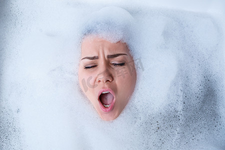 一个女孩在浴缸里的特写肖像和她脸上的白色泡沫。