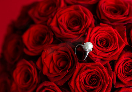 美丽的白金珍珠戒指和红玫瑰花束、奢华珠宝情人节和浪漫假期的爱情礼物