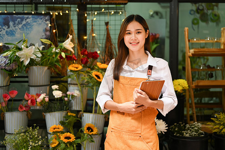 自信的小企业主站在花店前，对着镜头微笑。