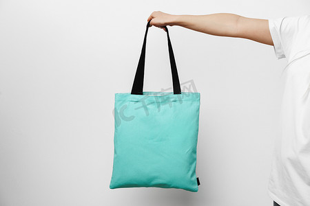 白色背景下女手拿着生态或可重复使用的购物袋