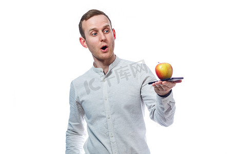 白种人男性商人拿着黑色手机，拿着红黄色苹果。