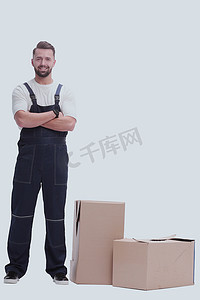 负责摄影照片_穿着工作服的严肃男子站在箱子旁边。