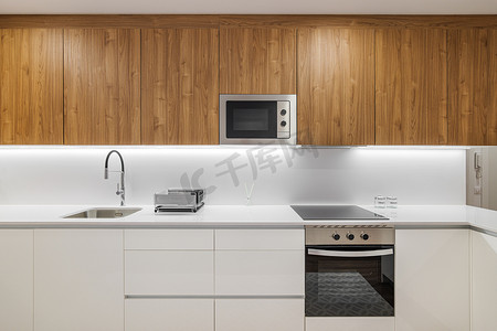 时尚的厨房配有白色现代家具和木制厨具橱柜。