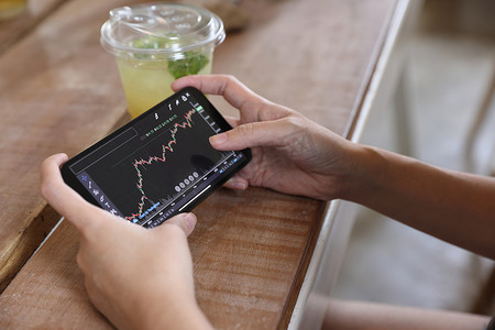 女手使用智能手机在咖啡店进行网上证券交易所交易，商业理念