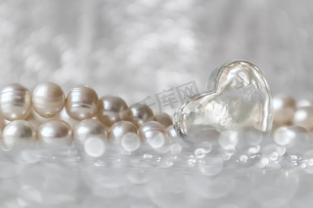 天然白色珍珠珠和闪闪发光的背景上的透明心