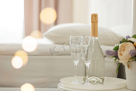 香槟图案摄影照片_酒店房间里有两个杯子和一瓶香槟。