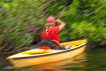 年轻女子在大沼泽地国家公园划皮划艇，具有运动模糊效果