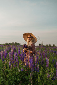 一位戴着草帽的美丽女子走在开满紫色花朵的田野里。